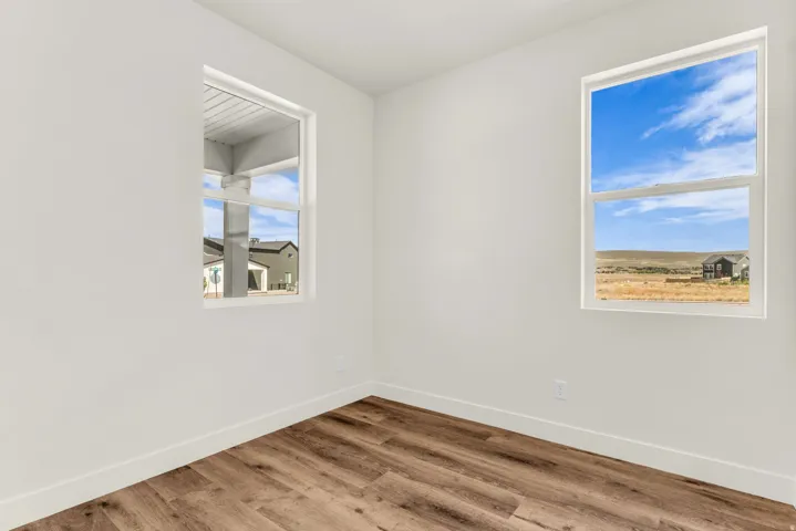 Wood-finish flooring with white walls and trim, complemented by two windows providing natural light