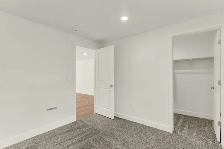 Wall-to-wall carpeting, overhead recessed lighting, and a built-in closet with shelving