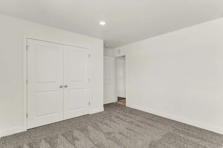 Recessed ceiling lighting, white walls, two-panel interior doors, gray carpet flooring, and white trim