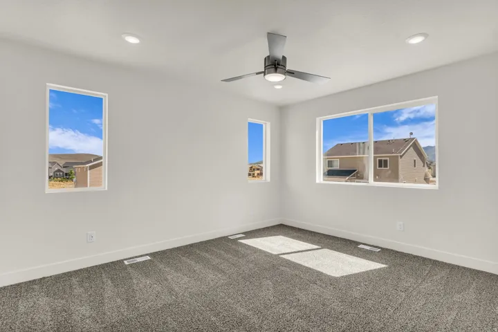 Recessed lighting, modern ceiling fan, multiple windows, white walls, and gray carpet