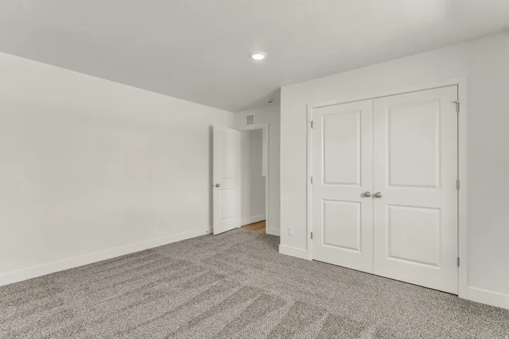 Wall-to-wall carpeting with a neutral finish, recessed lighting, and white bi-fold closet doors