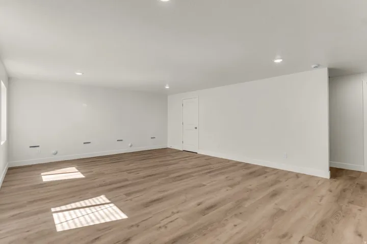 Recessed ceiling lighting, wood-finish flooring, and white walls