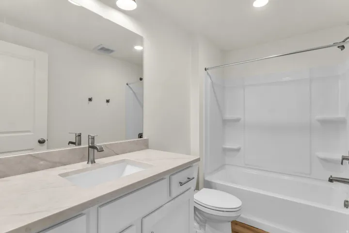 White vanity with a rectangular undermount sink, a gray-veined countertop, and a brushed nickel faucet