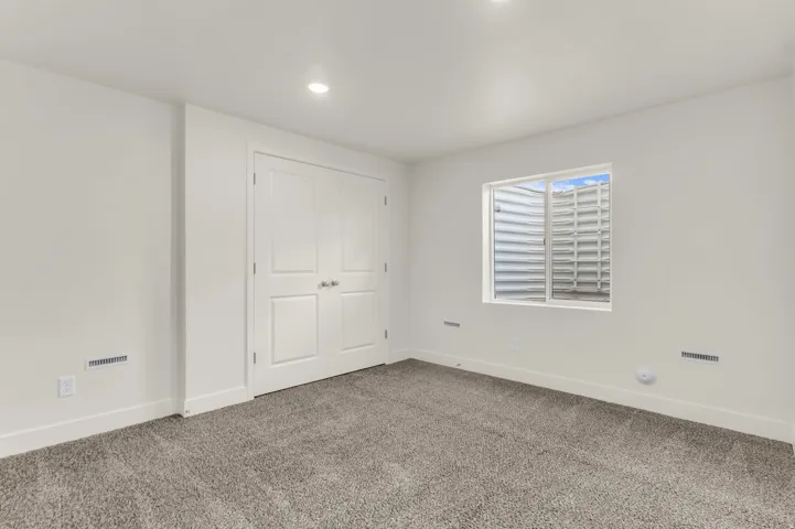 Bright room featuring light gray carpeting, white walls, double panel doors, and recessed lighting