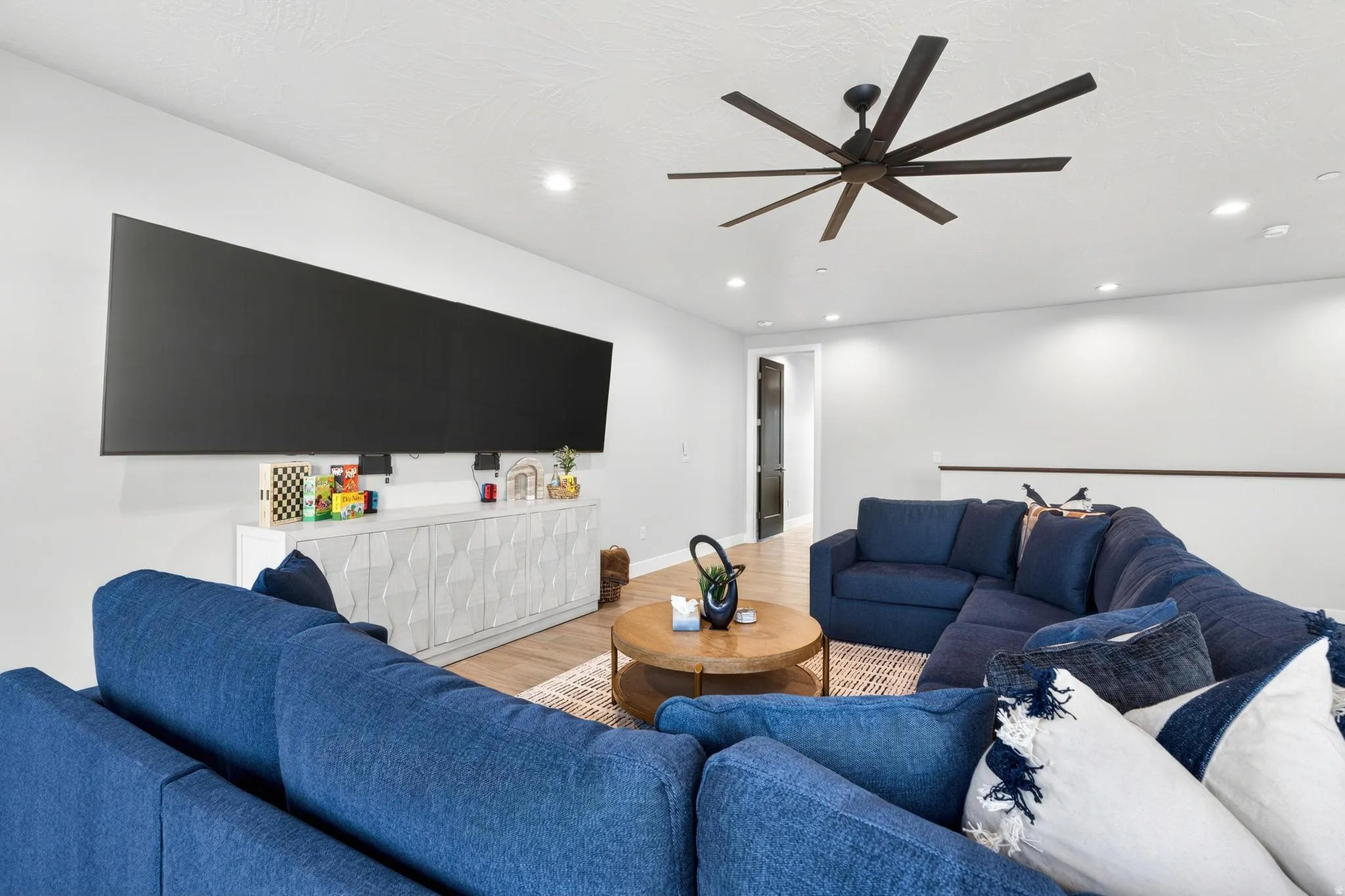 Spacious room featuring wood-finish flooring, recessed lighting, and a large ceiling fan