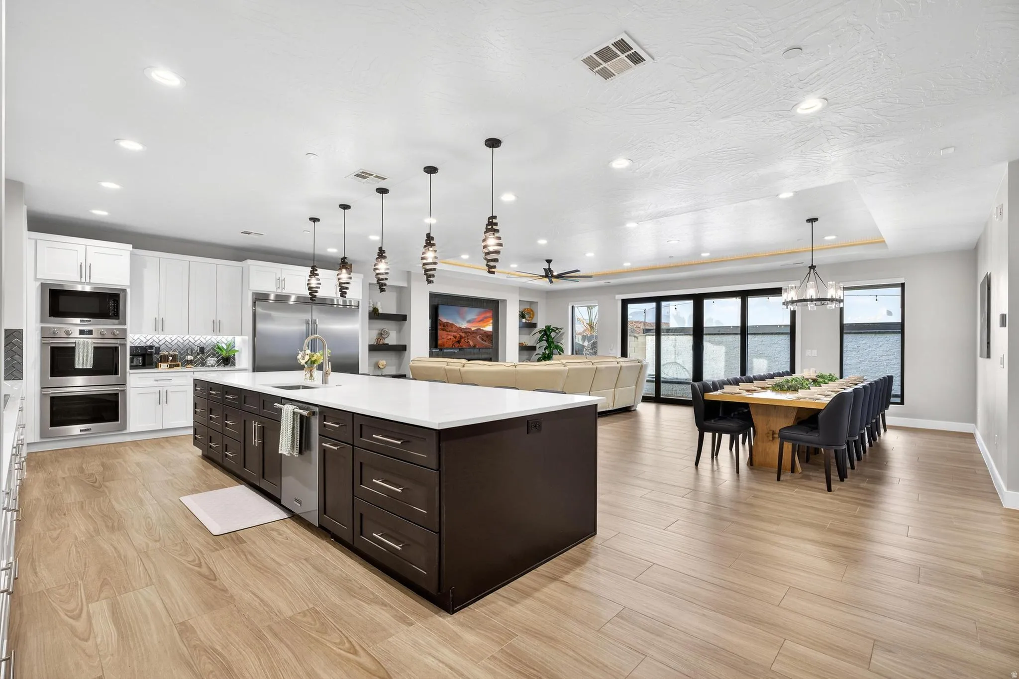 Expansive kitchen island with white countertop, integrated sink, and dark wood cabinetry