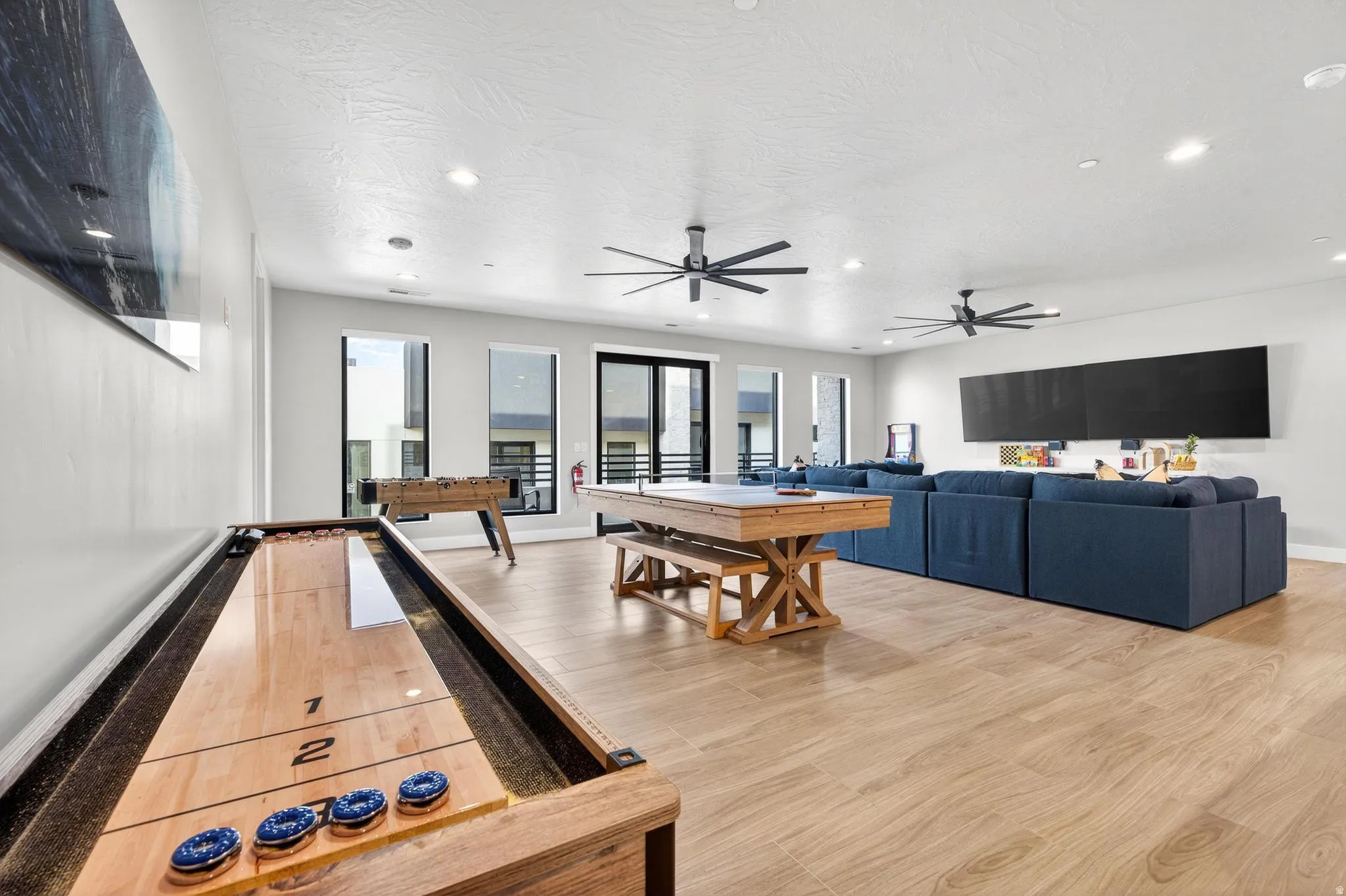 Expansive open-concept room featuring light wood-finish flooring, multiple windows, and recessed lighting