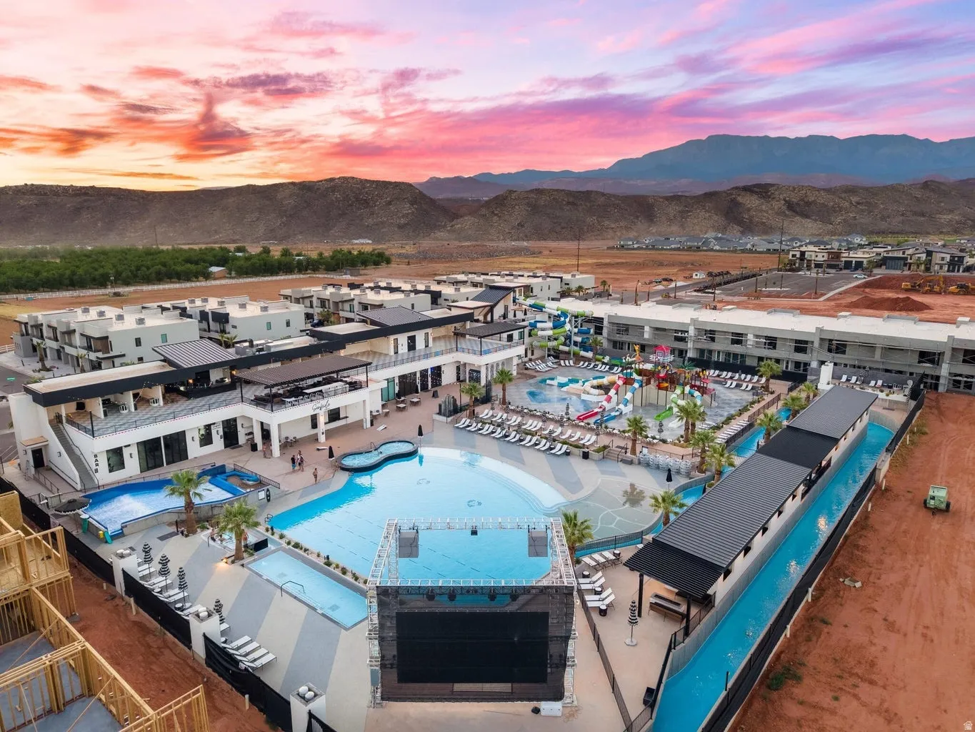 Expansive resort-style pool area featuring multiple swimming pools, a water park with slides, a lazy river, and a large outdoor screen