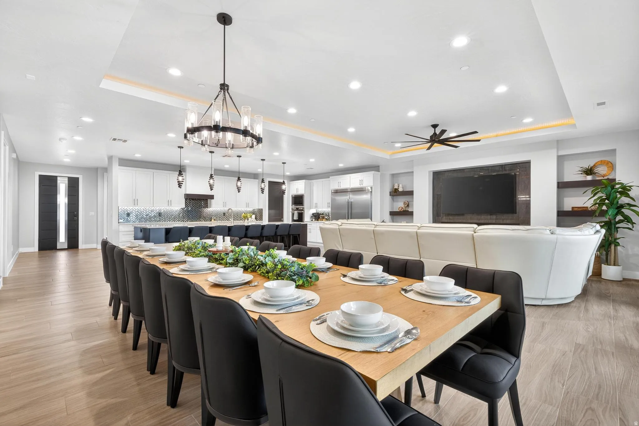 Open concept interior with wood-finish flooring, recessed lighting, a modern chandelier, and a built-in media wall