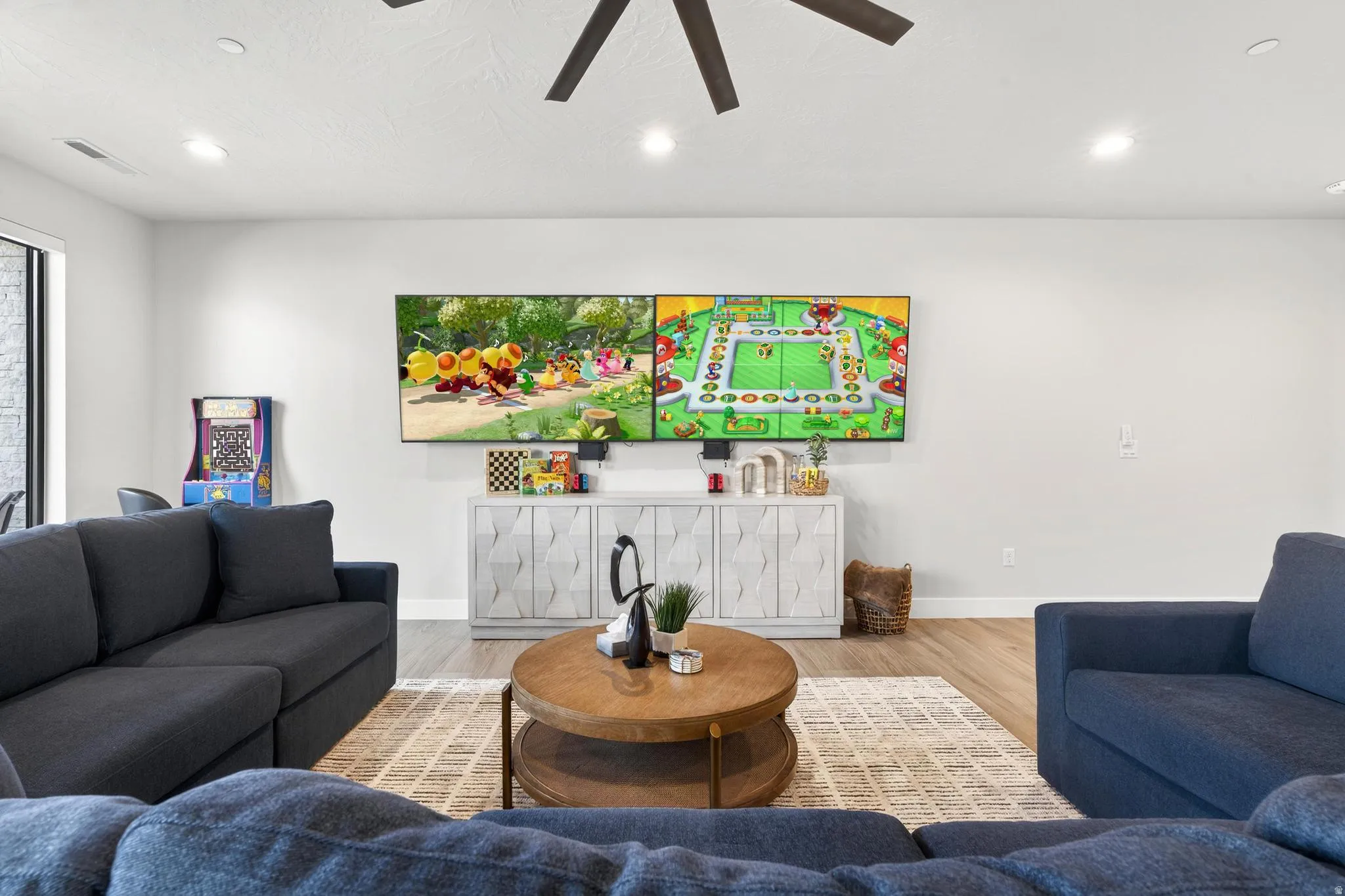 Spacious living area featuring light-toned walls, wood-finish flooring, and recessed lighting