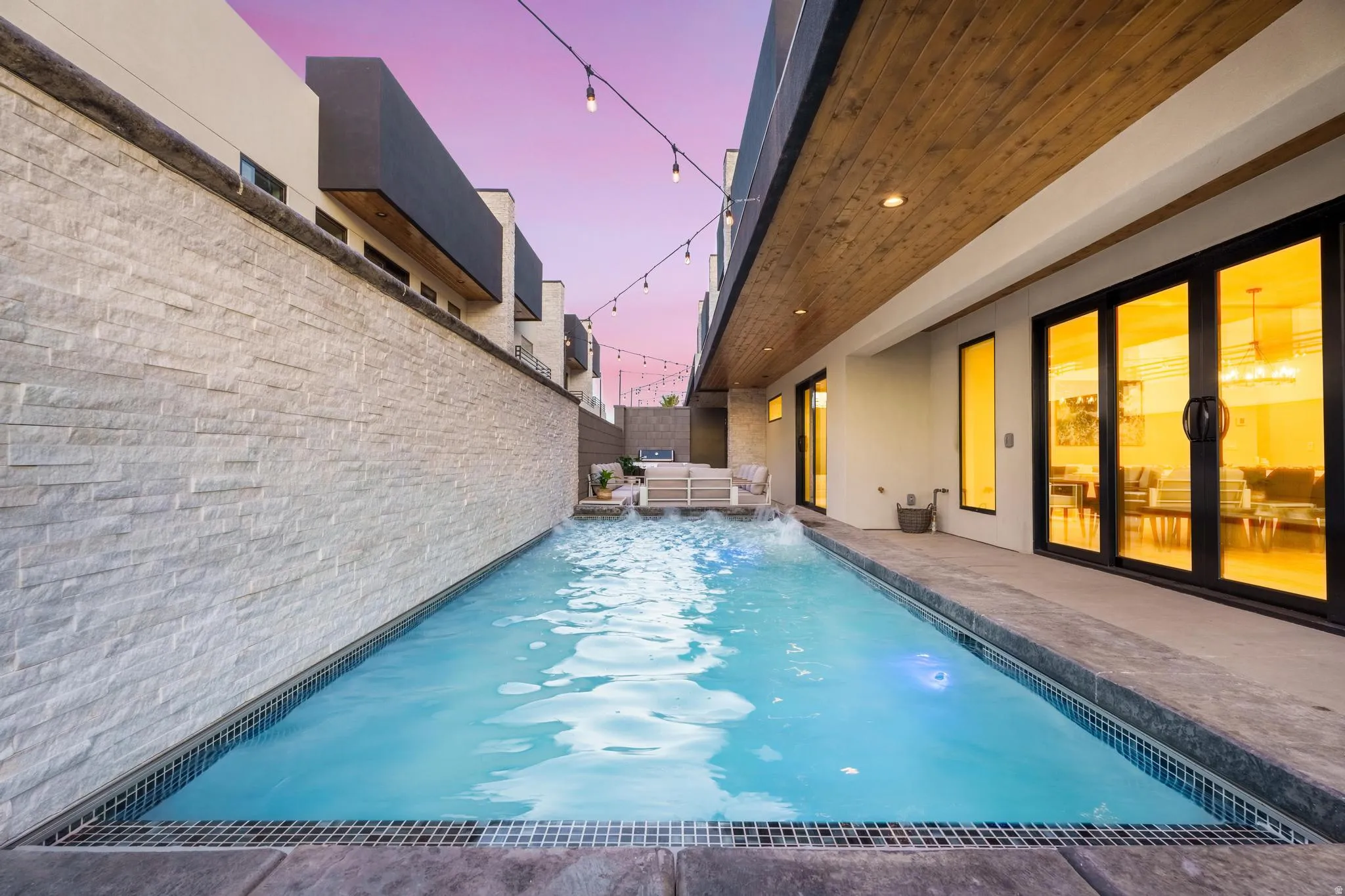 Lap pool with a stone-clad wall and a wide concrete surround