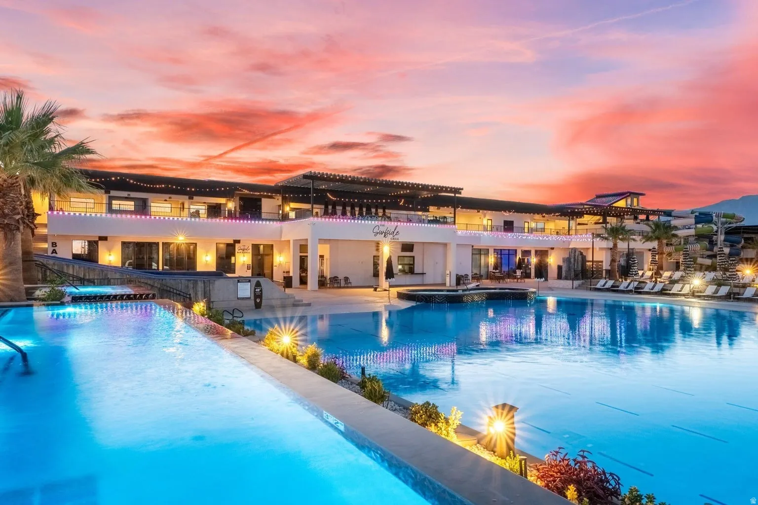 Expansive outdoor pool area featuring multiple swimming pools, a raised spa, and abundant lounge seating