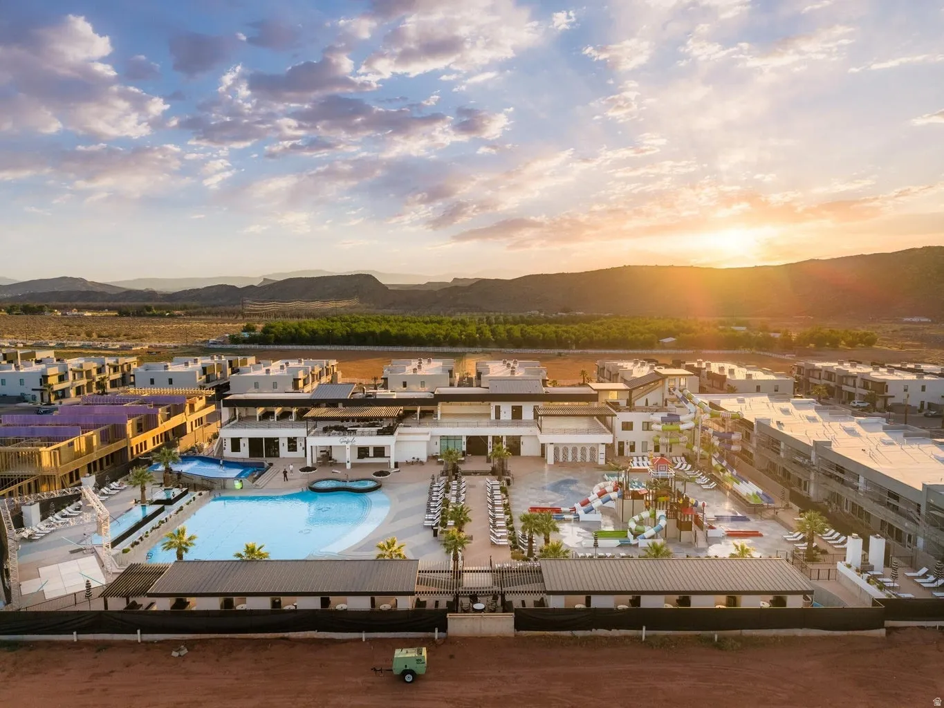 Expansive resort-style swimming pools with multiple water slides, numerous lounge chairs, and mature palm trees