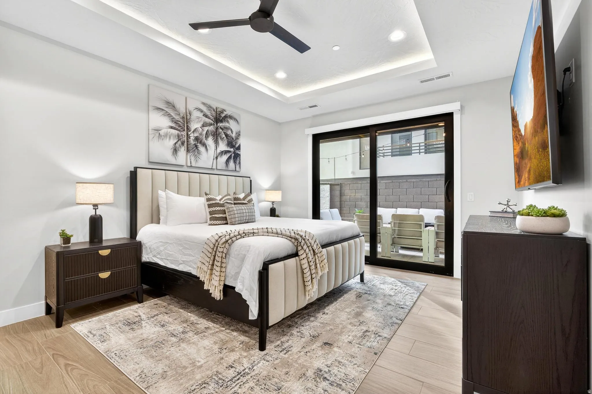 Primary Bedroom with Coffered Ceiling and Glass Sliding DoorsThis bright primary bedroom showcases a coffered ceiling with integrated recessed lighting and a ceiling fan, creating architectural depth and visual interest