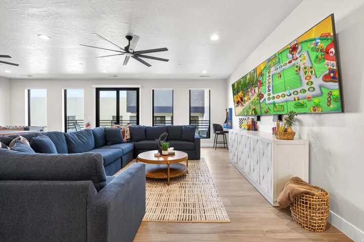Spacious living area featuring high ceilings, wood-finish flooring, recessed lighting, and a modern ceiling fan