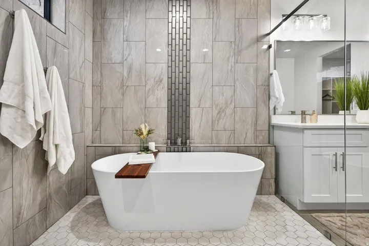 Freestanding soaking tub with a tiled surround and feature wall, hexagon tile flooring, and a glass-enclosed shower
