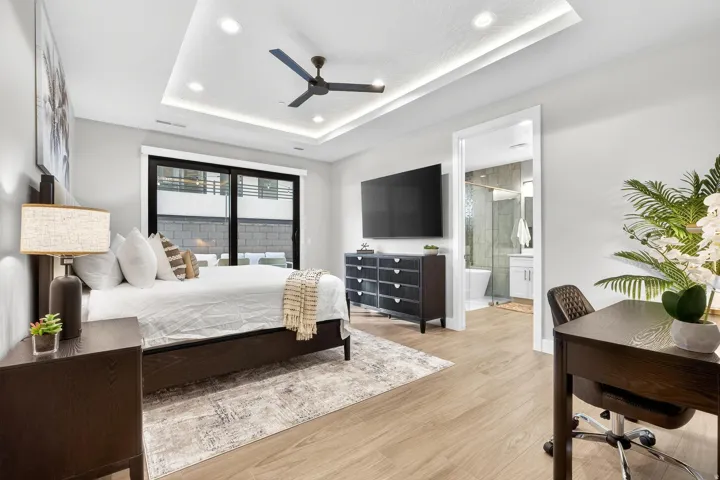 Recessed lighting, wood-finish flooring, tray ceiling with cove lighting, sliding glass door, and an integrated ceiling fan