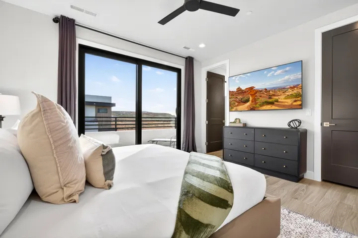 Sliding glass doors to a private balcony, wood-finish flooring, and a ceiling fan