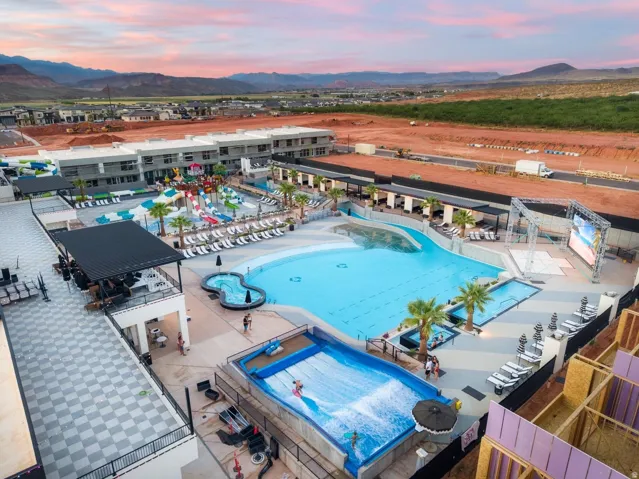 Expansive aquatic amenity featuring a large swimming pool, water slides, wave simulator, and multiple lounge areas