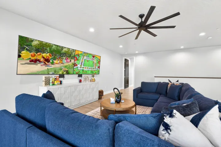 Spacious room featuring wood-finish flooring, a contemporary ceiling fan, recessed lighting, and a built-in media console