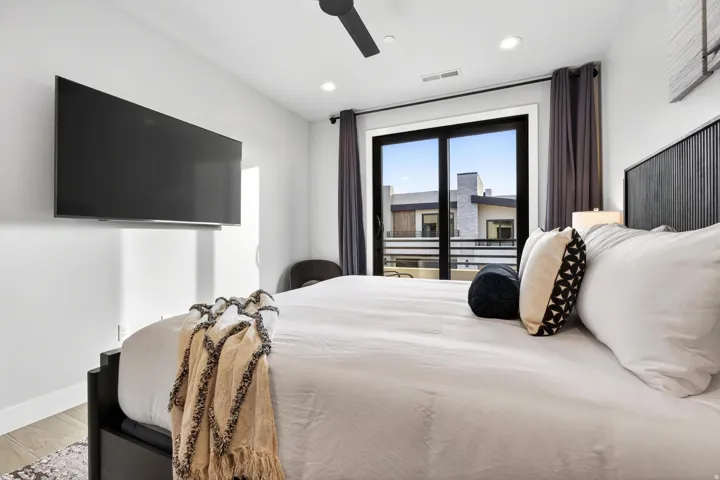Recessed lighting, ceiling fan, wall-mounted television, full-light glass door, and dark drapery