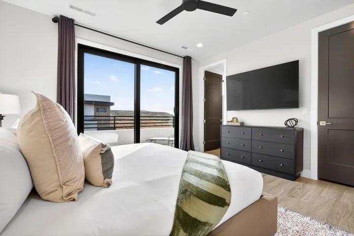 Sliding glass door to private balcony, wood-finish flooring, recessed lighting, ceiling fan, and dark paneled doors