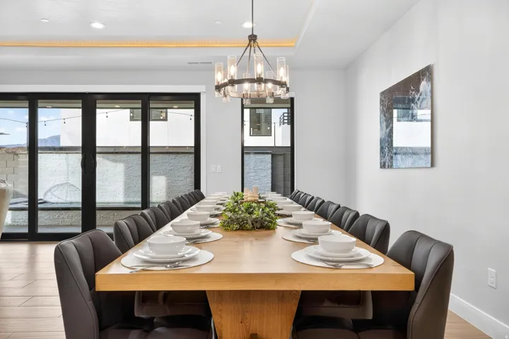 Recessed lighting, wood-finish flooring, and a contemporary chandelier illuminate this dining area