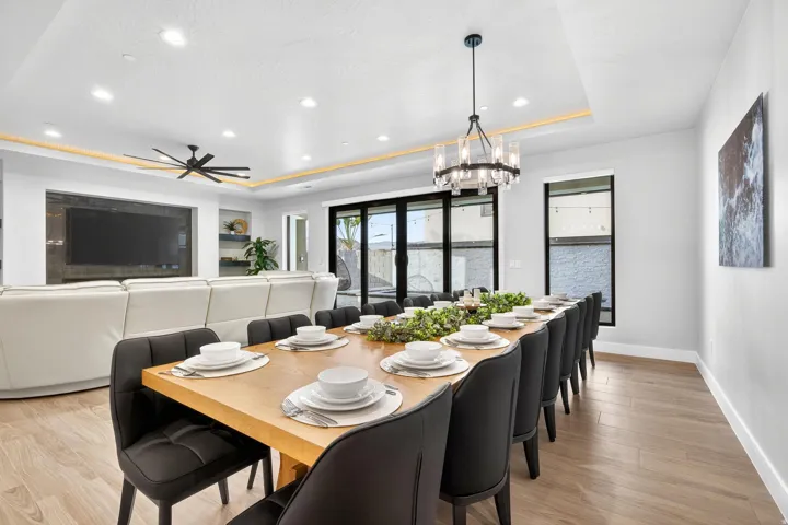Recessed lighting, wood-finish flooring, and a contemporary chandelier illuminate this dining area