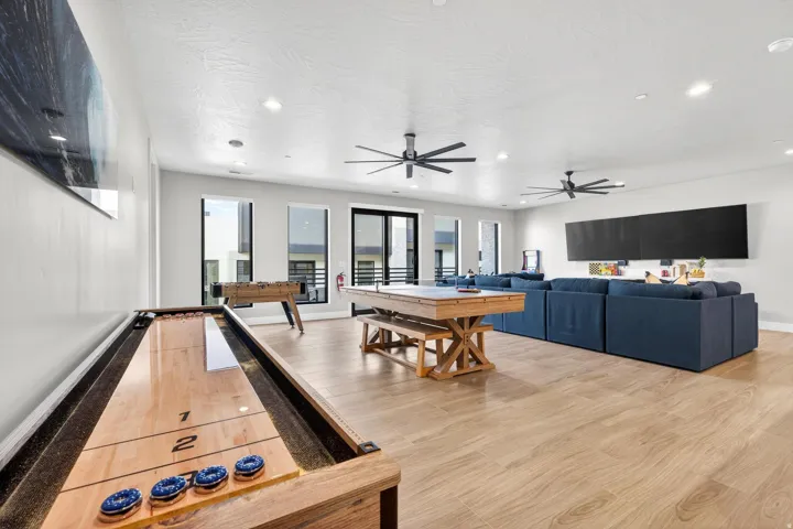 Expansive open-concept room featuring light wood-finish flooring, multiple windows, and recessed lighting