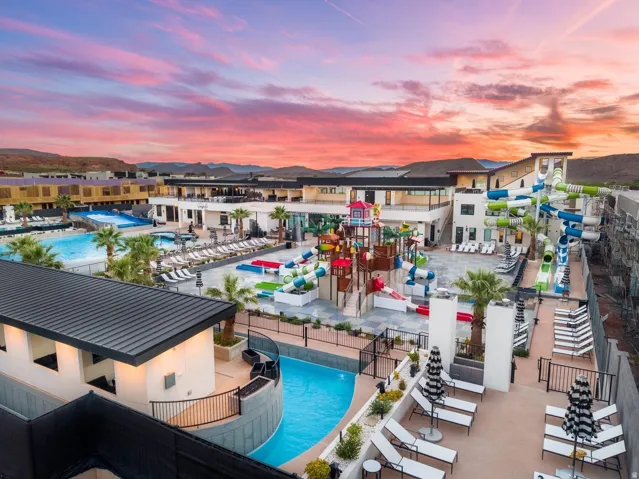 Expansive resort-style pool area featuring multiple swimming pools, water slides, and a wave simulator