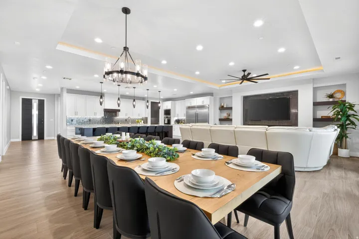 Open concept interior with wood-finish flooring, recessed lighting, a modern chandelier, and a built-in media wall
