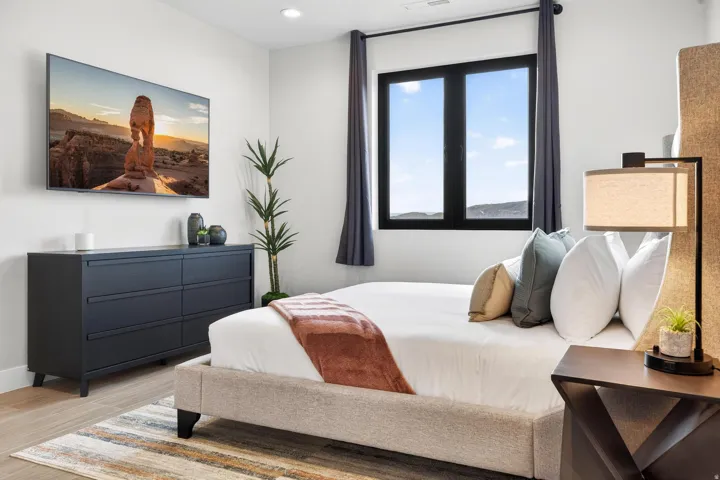 Recessed lighting, large window with dark trim, wood-finish flooring, and a wall-mounted television