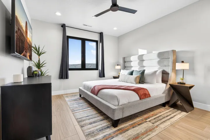 Recessed ceiling lighting, a contemporary ceiling fan, and large black-framed windows complement the light wood-finish flooring