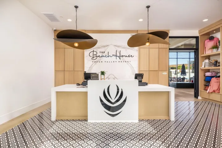 Reception area featuring patterned floor tiling, a white and wood-finish desk, and two unique pendant light fixtures