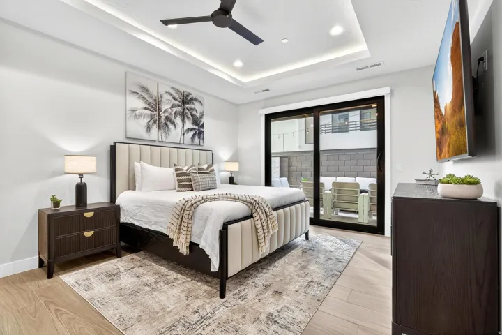 Primary Bedroom with Coffered Ceiling and Glass Sliding DoorsThis bright primary bedroom showcases a coffered ceiling with integrated recessed lighting and a ceiling fan, creating architectural depth and visual interest