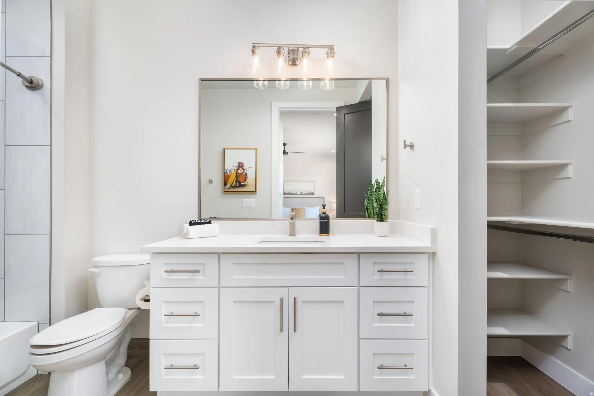 White vanity with a single sink, light-colored countertop, and brushed nickel hardware