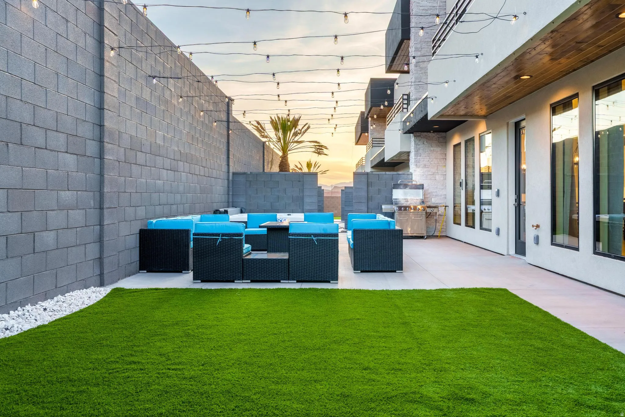 Patio area featuring a built-in grill station, concrete hardscaping, artificial turf, and block wall perimeter