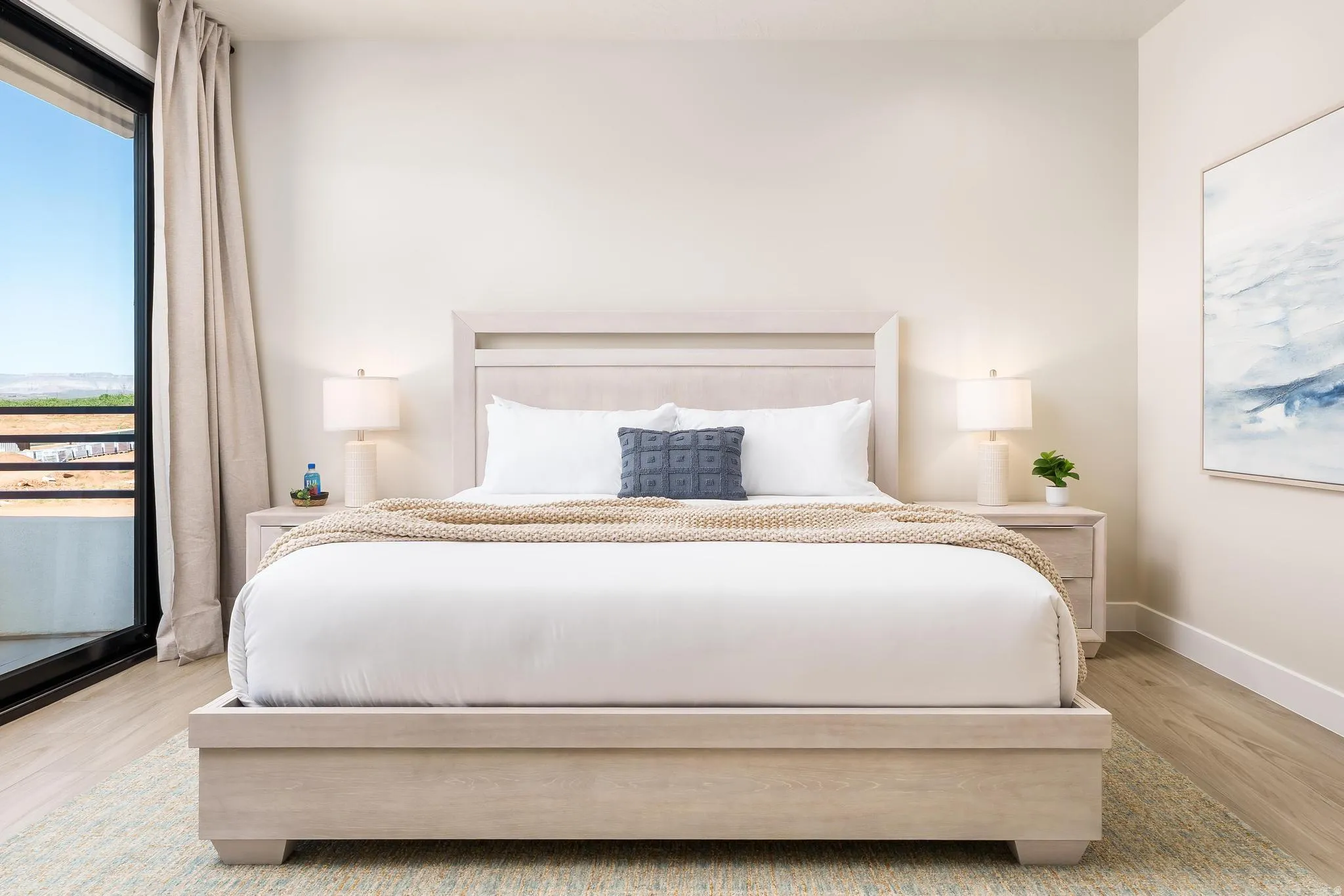 Full-height glass sliding door, light-toned wood-finish flooring, recessed ceiling lighting, light-colored walls, and a light-toned wood headboard