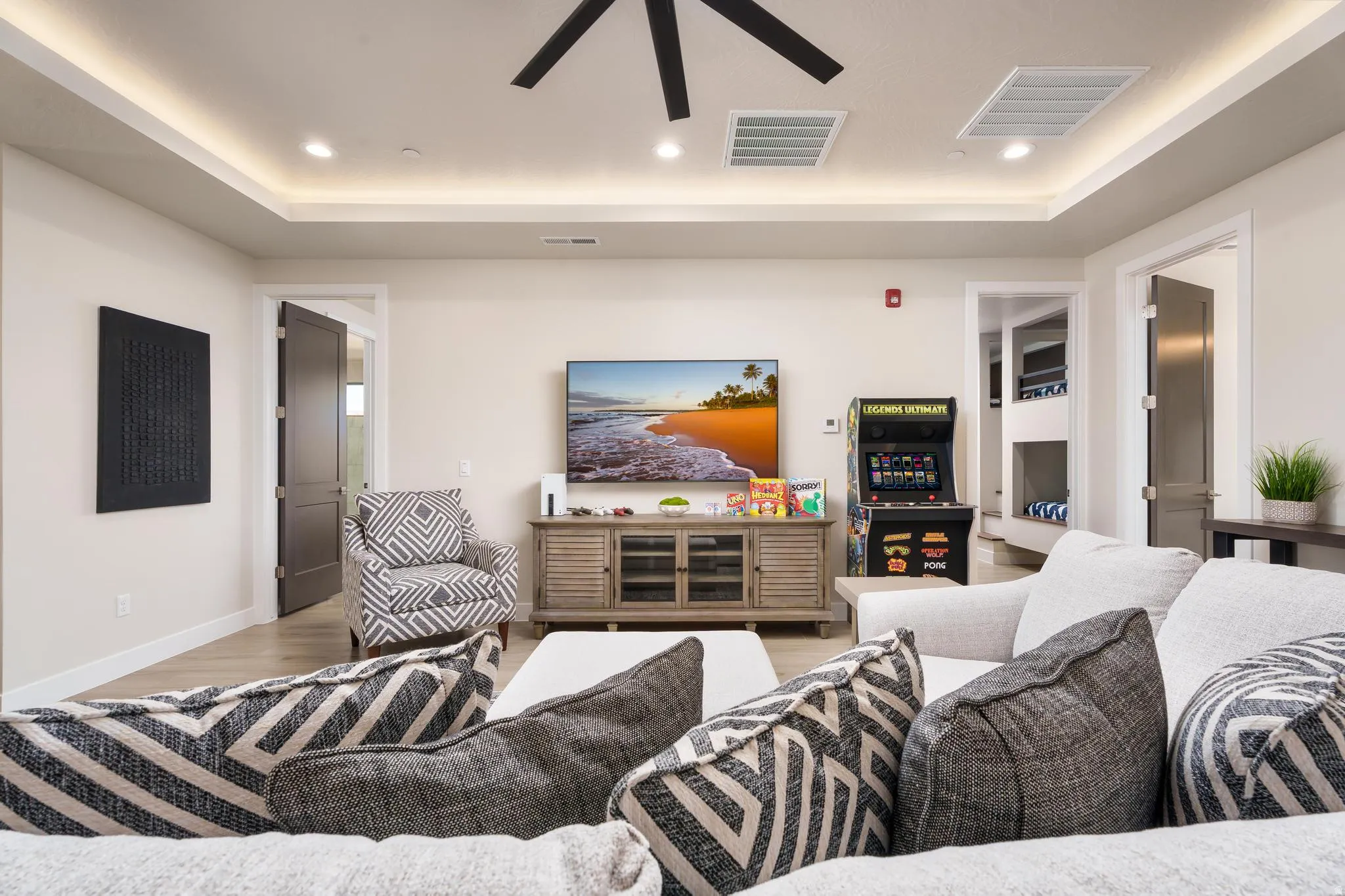 Recessed lighting, ceiling fan, crown molding with accent lighting, wood-finish flooring, and white baseboards