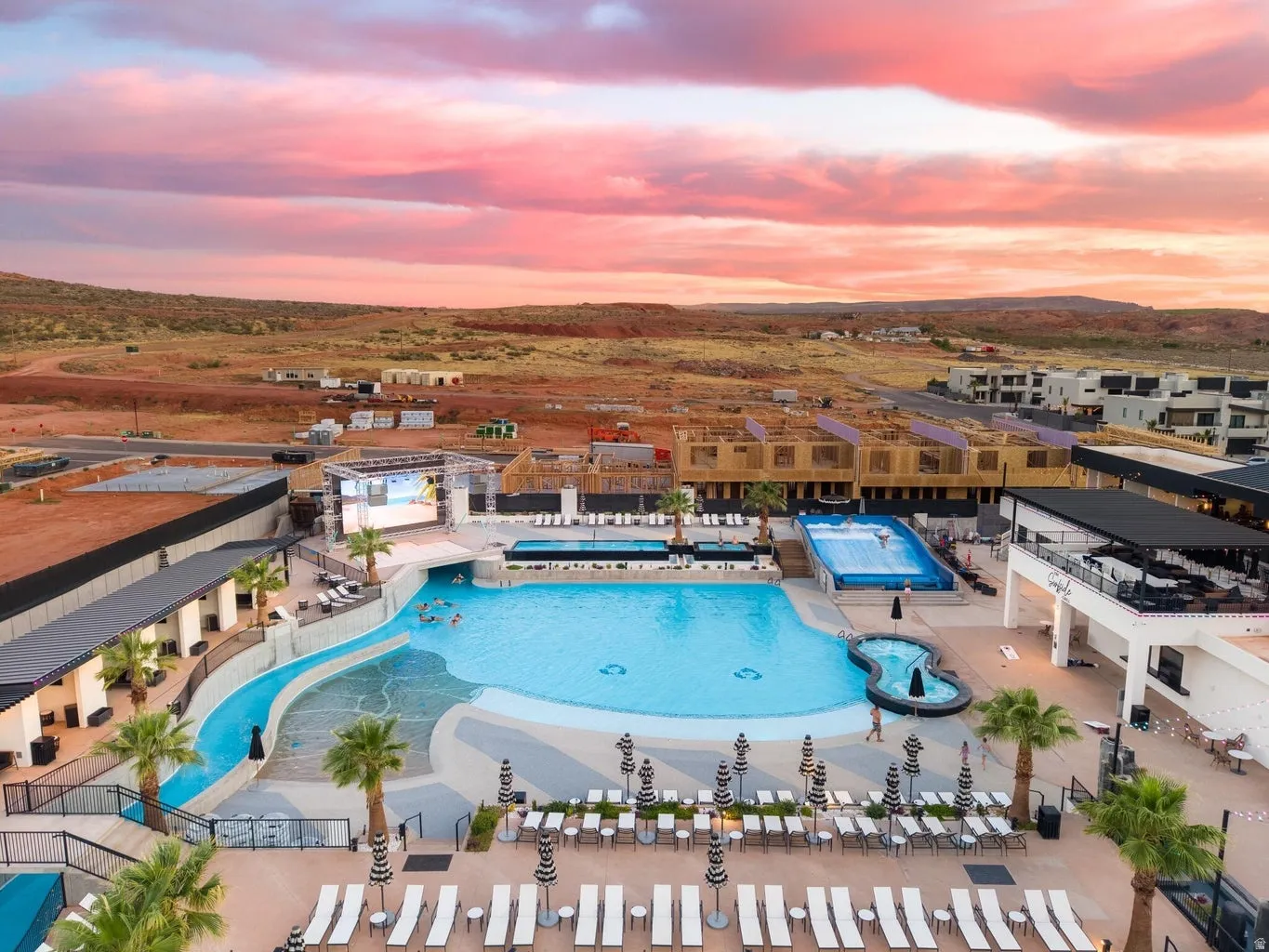 Expansive outdoor aquatic area featuring a large swimming pool, integrated water slide, and wave simulator
