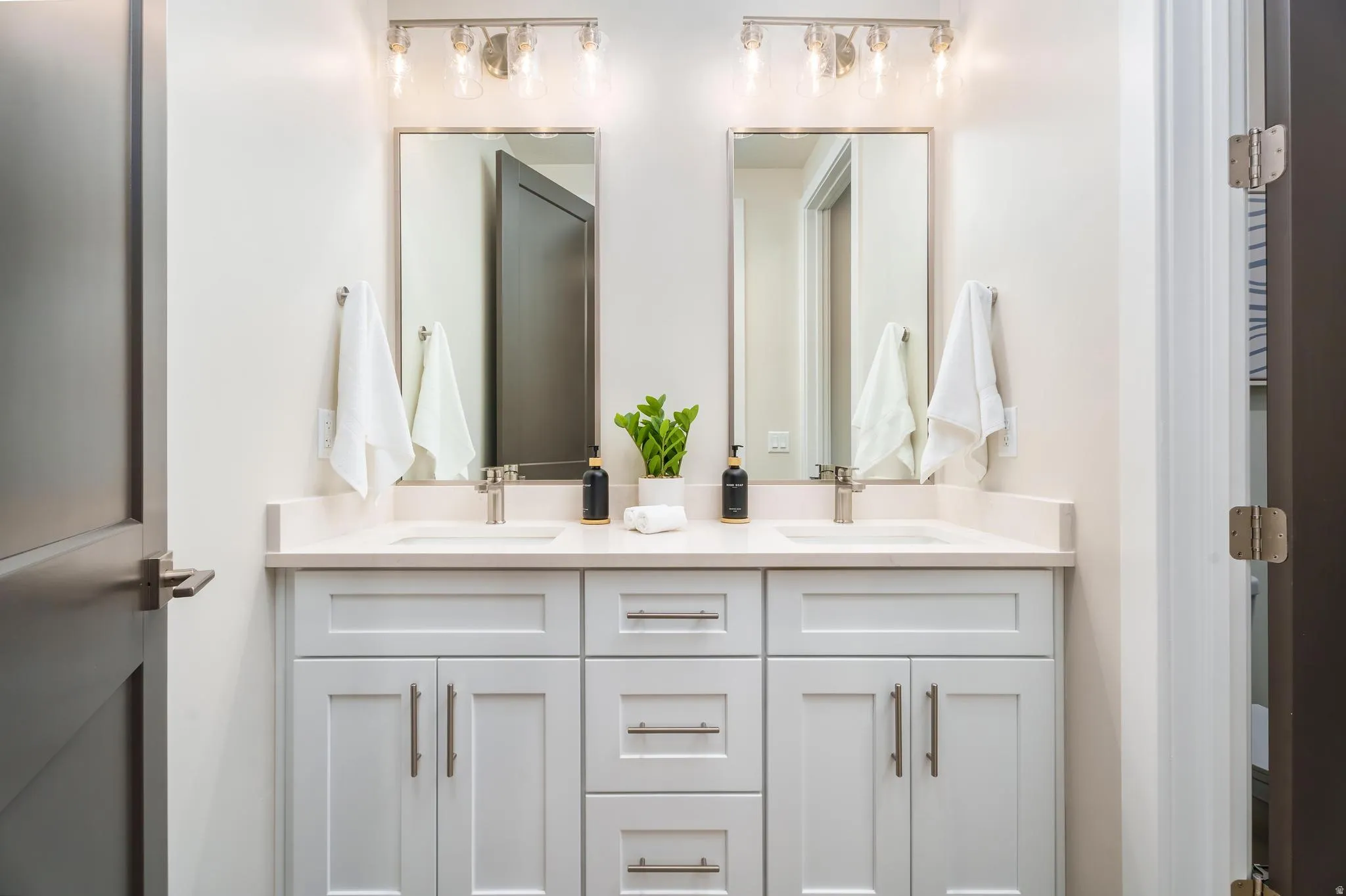 Dual vanity with white shaker-style cabinetry, undermount sinks, and brushed nickel hardware