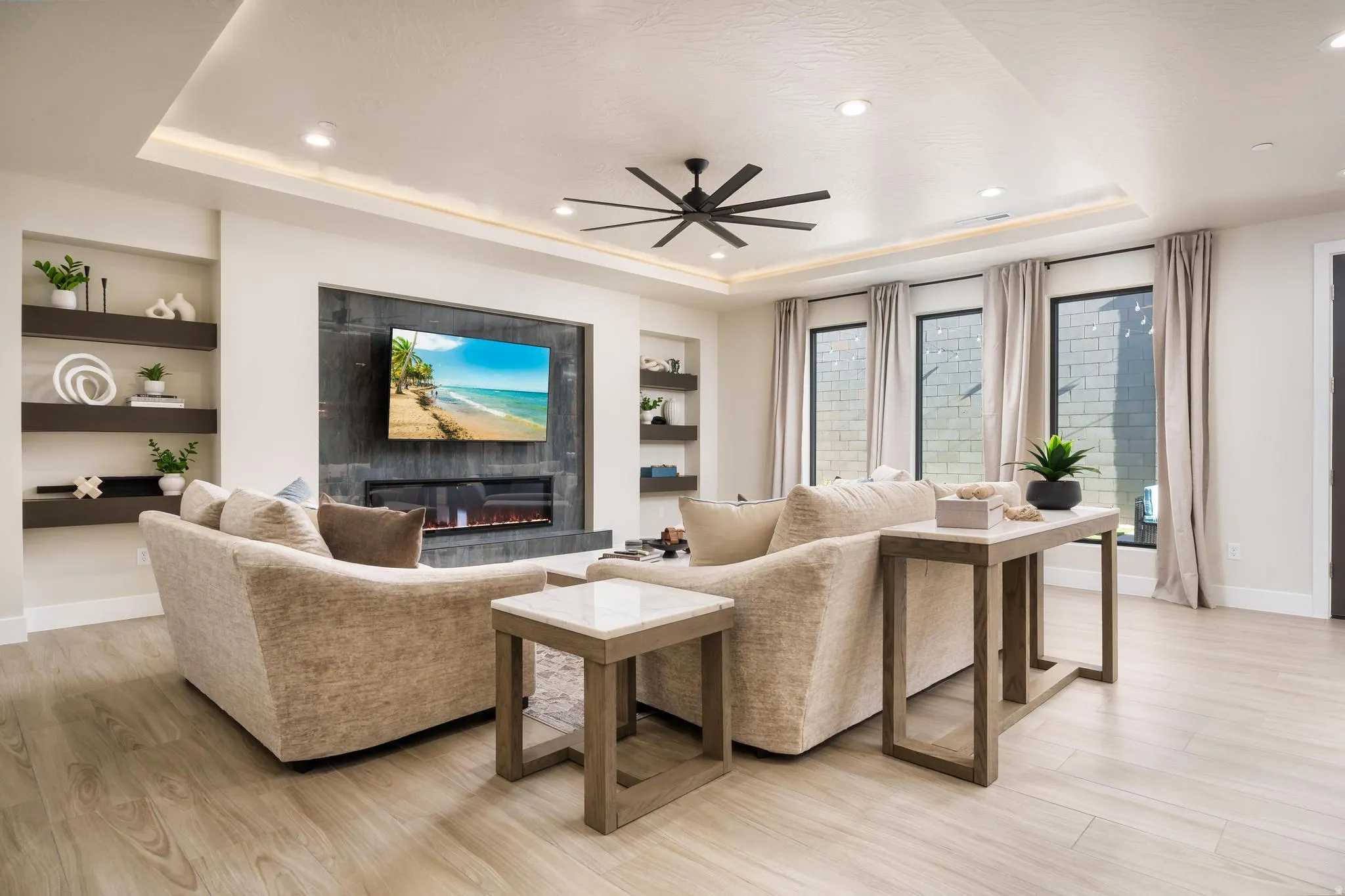 Recessed lighting, wood-finish flooring, built-in shelving, a modern electric fireplace, and a ceiling fan