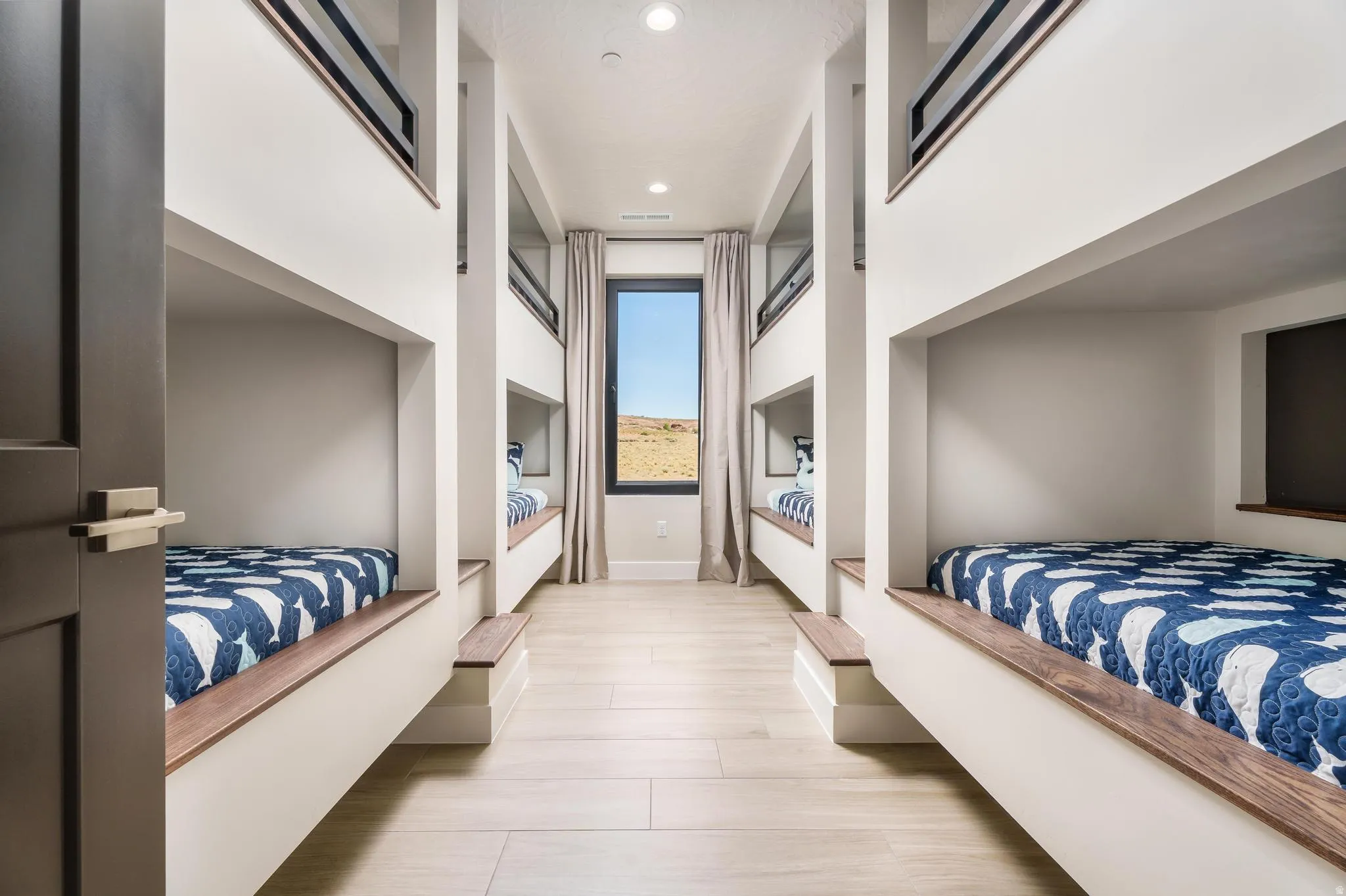 Built-in bunk beds with wood-finish trim, recessed lighting, and a single window with curtain panels