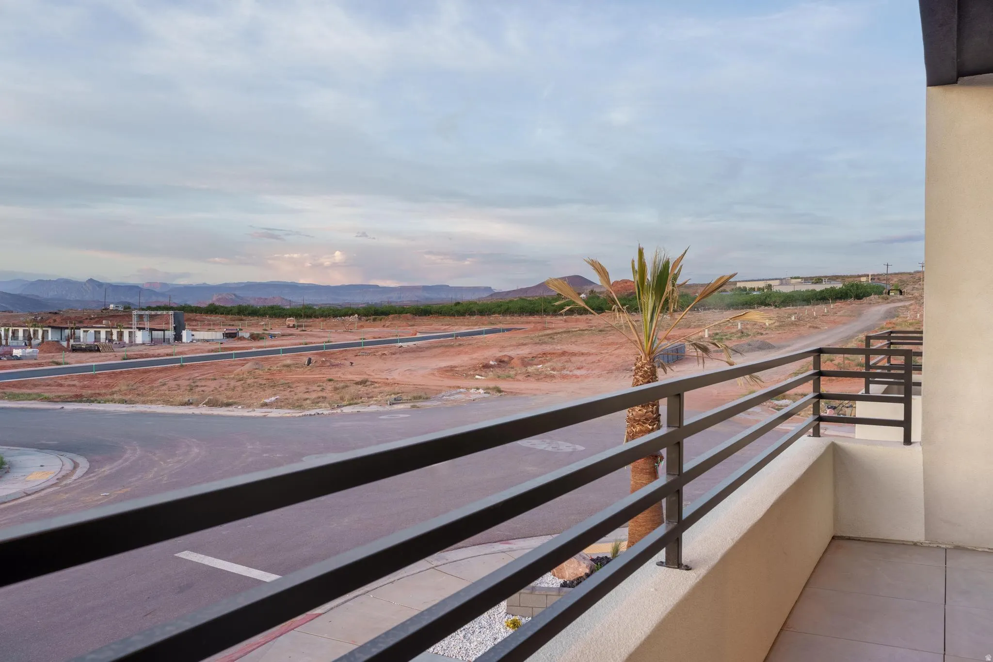 Balcony with horizontal metal railings, concrete flooring, and a desert landscape backdrop