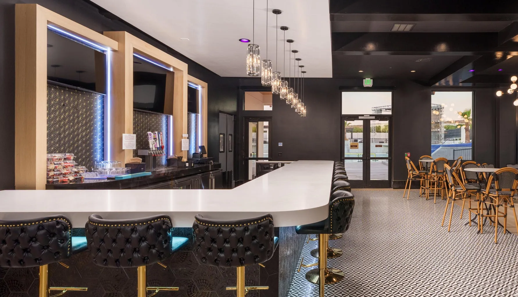 Extended bar counter with integrated seating, pendant lighting, geometric tile flooring, and multiple sets of glass double doors