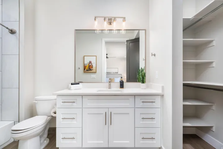 White vanity with a single sink, light-colored countertop, and brushed nickel hardware