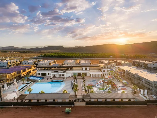 Expansive resort-style pool area featuring multiple swimming pools, a water park with slides, ample lounge seating, and surrounding multi-story buildings
