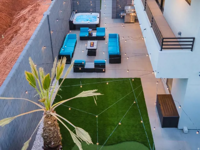 Backyard featuring a built-in hot tub, artificial turf, a putting green, and a privacy wall