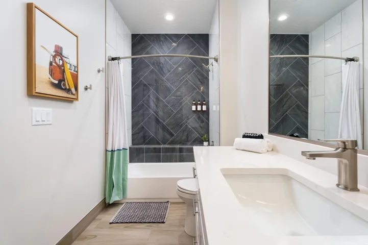 White vanity with integrated sink, brushed nickel faucet, and a large frameless mirror