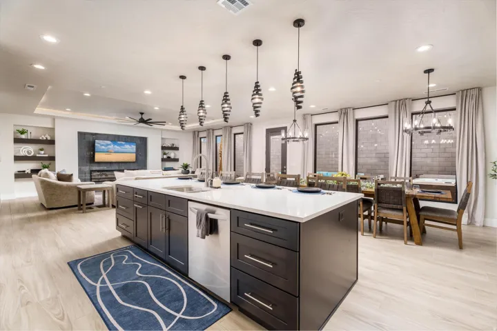 Spacious open-concept living area featuring an expansive kitchen island with a white countertop, dark wood-finish cabinetry, and pendant lighting